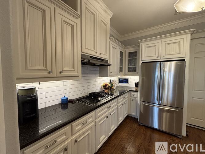 A kitchen with white cabinets and a stainless steel refrigerator.