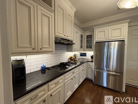A kitchen with white cabinets and a stainless steel refrigerator.
