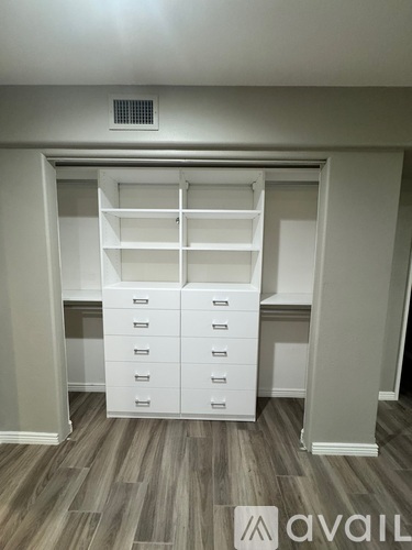 A white closet with drawers and shelves in a room.
