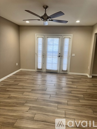 A room with a ceiling fan and wooden flooring.