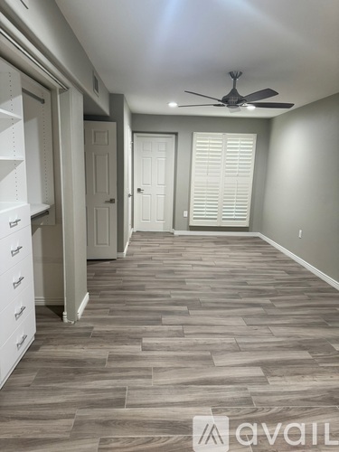 A room with a fan and a door with blinds.