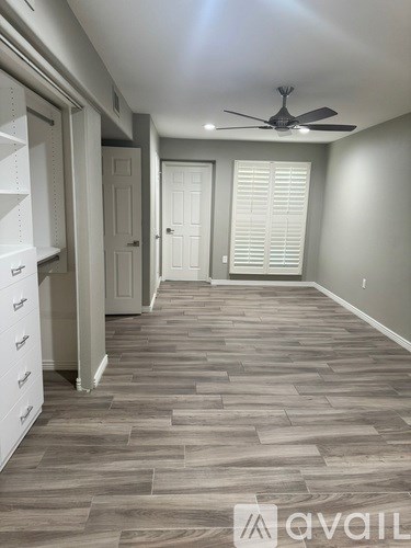 A room with a fan and a door with blinds.