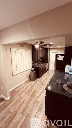 A kitchen with a black countertop and wooden flooring.