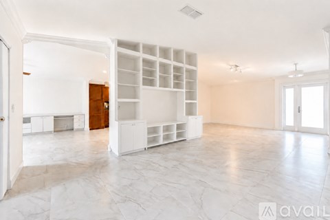 A spacious room with white marble flooring and a white built-in shelving unit.