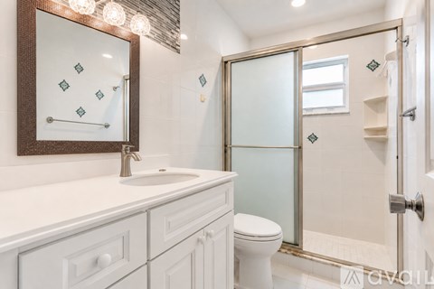 A bathroom with a white toilet and a mirror above a sink.