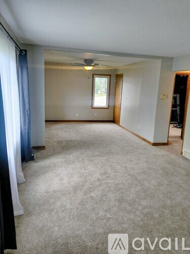 A spacious room with a carpeted floor and a window with a view outside.