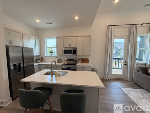 A kitchen with a white countertop and a sink, a refrigerator, a microwave, and a dining table with chairs.