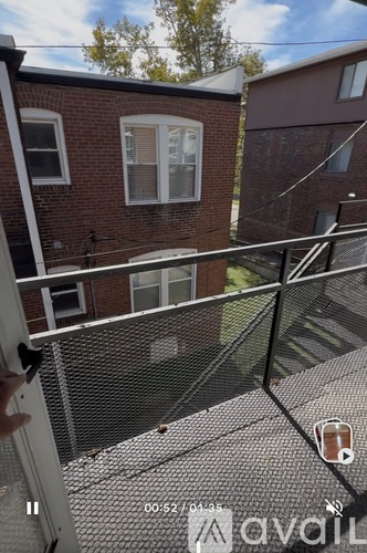 A balcony with a metal railing and a brick building in the background.