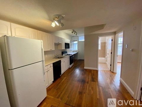 A kitchen with white appliances and wooden floors.