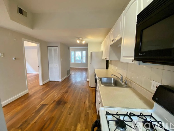 A kitchen with a stove, sink, and cabinets.