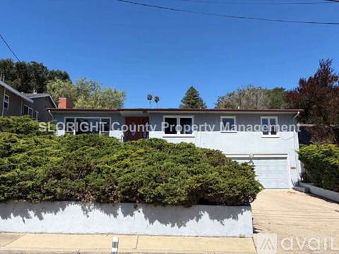 A white building with a sign that says "SLOUGHT COUNTY PROPERTY MANAGEMENT" in front of a green hedge.