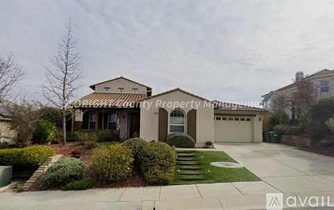 A house with a well-maintained lawn and a driveway in front.