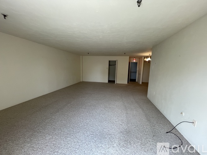 A large empty room with carpeted floor and white walls.