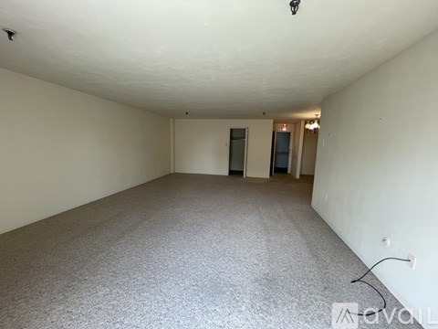 A large empty room with carpeted floor and white walls.