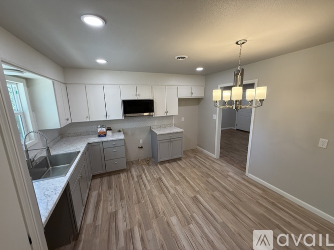 A kitchen with wooden floors and white cabinets.
