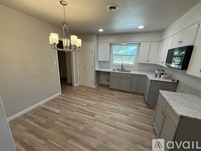 A kitchen with wooden flooring and a chandelier.