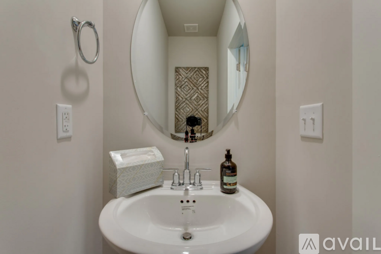 A bathroom sink with a mirror above it and a bottle of soap on the counter.
