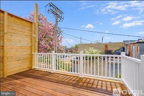 A wooden deck with a white railing and a view of a street with cars and buildings.