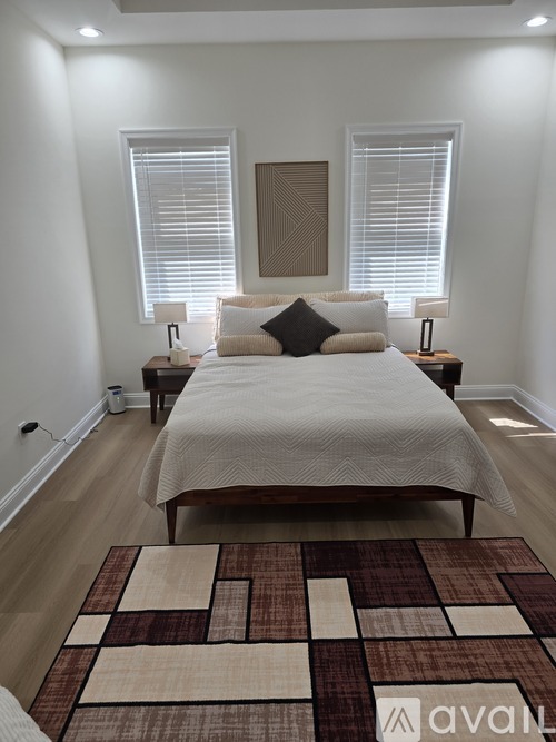 A bedroom with a large bed and a rug on the floor.