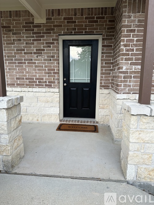 A black door with a glass window is set in a brick wall.