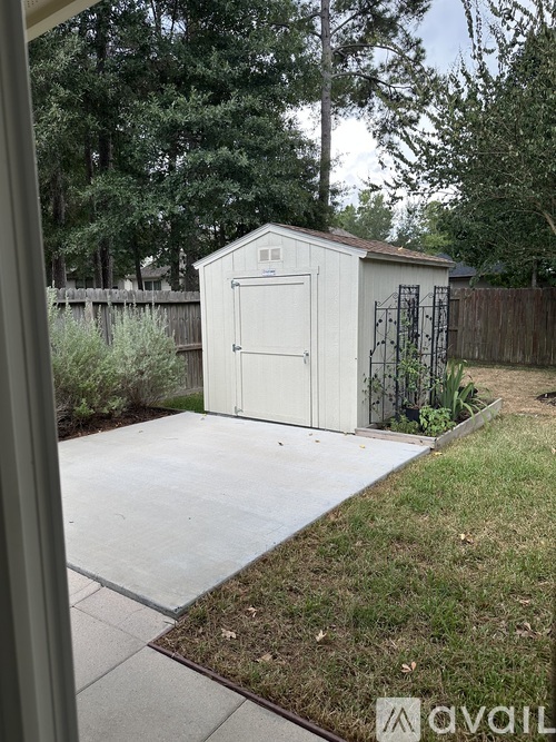 A small white shed with a brown fence in the background.