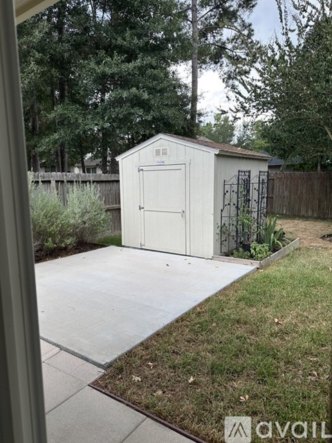A small white shed with a brown fence in the background.