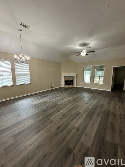 A spacious room with wooden flooring and a fireplace.