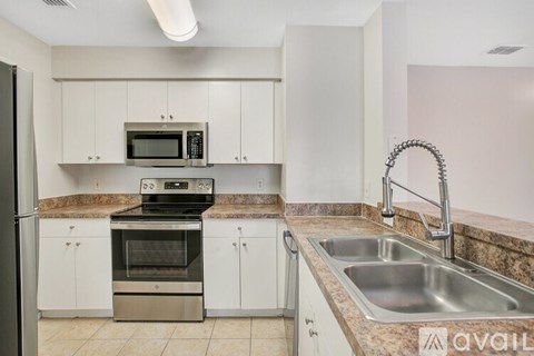 A kitchen with a stainless steel refrigerator, microwave, oven, and sink.