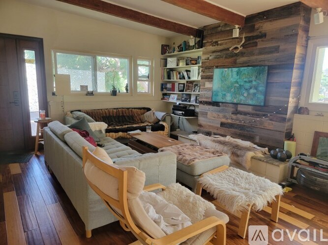 A living room with a couch, chair, and a wooden wall.