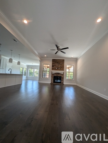 A spacious room with wooden floors and a ceiling fan.