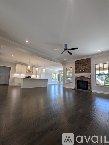 A spacious living room with a fireplace and a ceiling fan.
