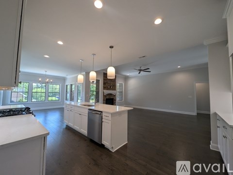 A modern kitchen with white cabinets and a wooden floor.