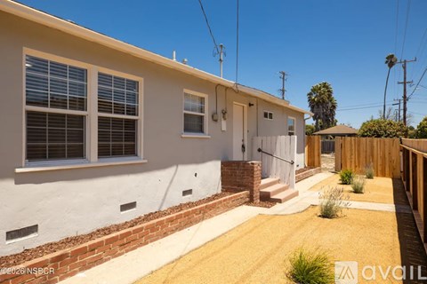 A house with a white exterior and a brown brick border.