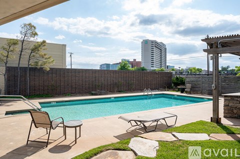 A pool with a chair and table in front of a fence.