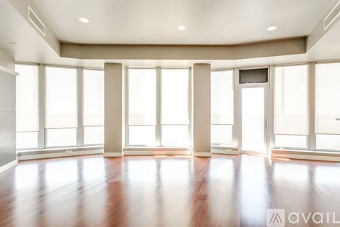 A spacious room with wooden floors and large windows.