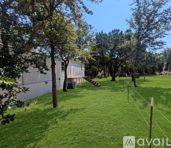 A backyard with a lawn, trees, and a fence.