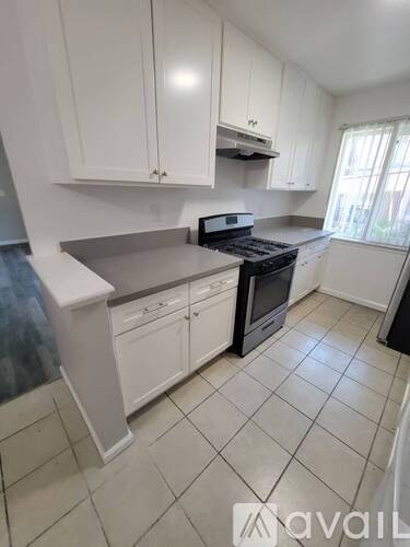 A kitchen with white cabinets and a black stove top oven.