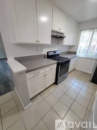 A kitchen with white cabinets and a black stove top oven.