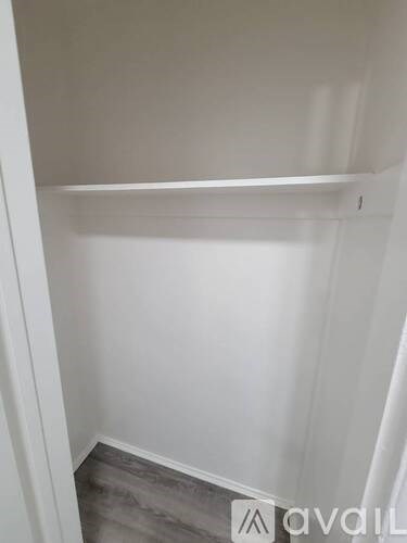 A white wall with a shelf and a grey floor.
