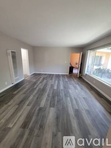 A room with wooden flooring and a large window.