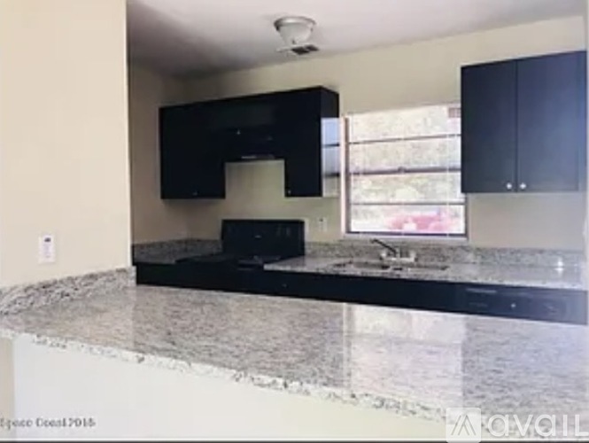 A kitchen with black cabinets and a granite countertop.