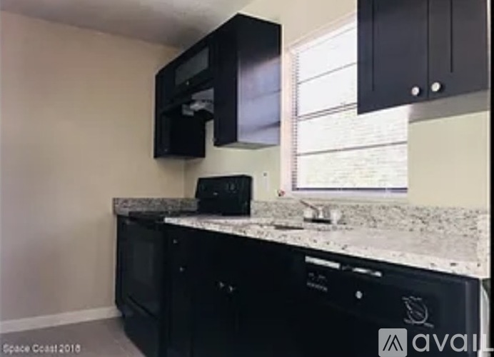 A kitchen with black cabinets and a granite countertop.