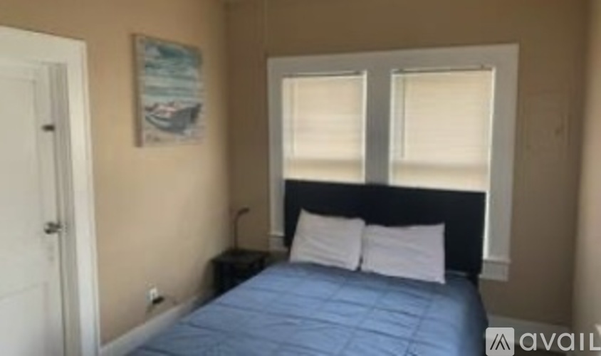 A bedroom with a bed, nightstand, and a picture on the wall.