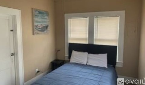 A bedroom with a bed, nightstand, and a picture on the wall.