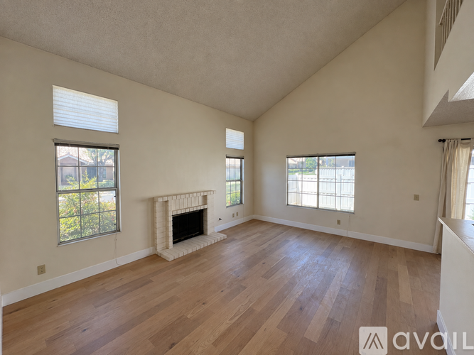 A spacious room with wooden floors and a fireplace.