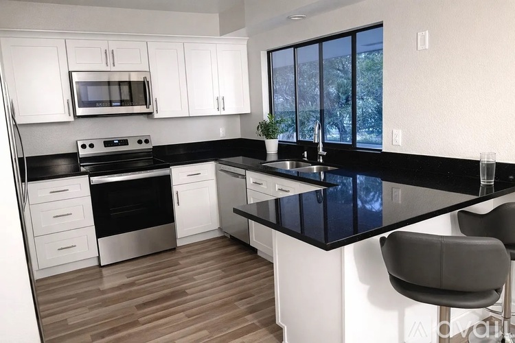 A modern kitchen with white cabinets and black countertops.