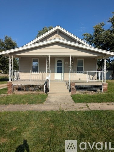 A small house with a porch and a fence.