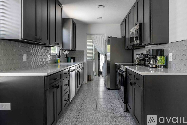A kitchen with black cabinets and a tiled floor.