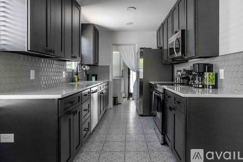 A kitchen with black cabinets and a tiled floor.