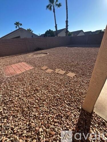 A backyard with a gravel ground and a small patch of grass.